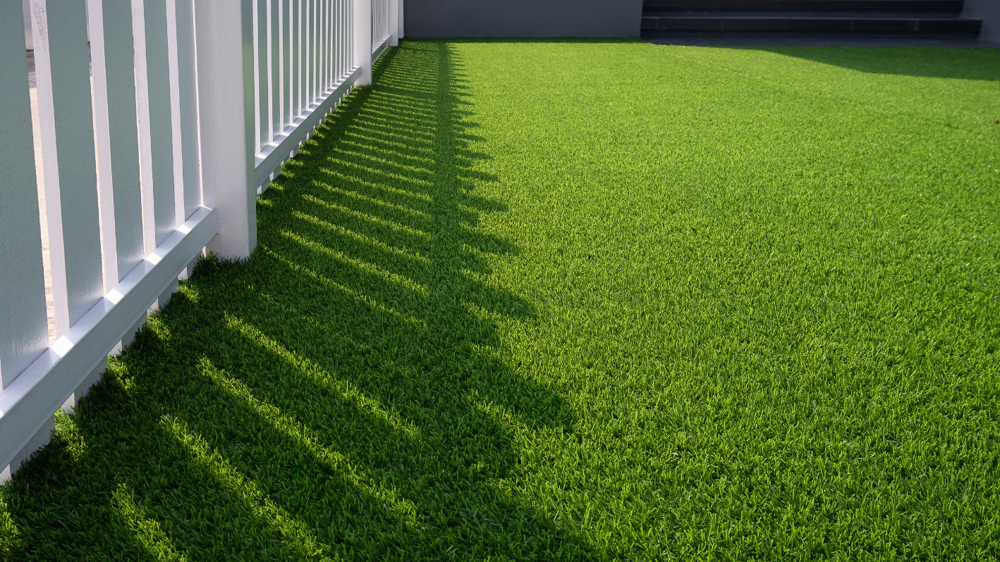 A white fence sitting next to a lush green field